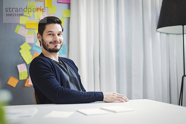 Portrait of confident mid adult businessman sitting at desk in office