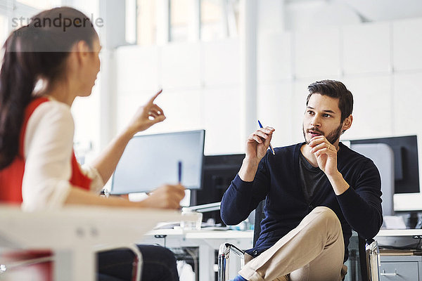 Businessman discussing with female colleague in office