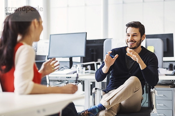 Happy businessman discussing with female colleague in office