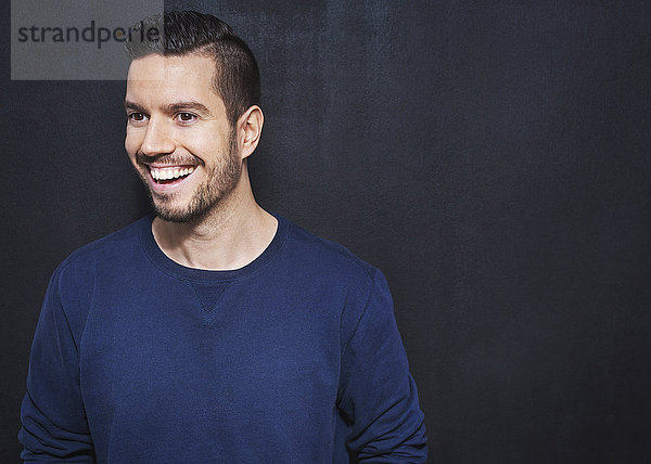 Smiling mid adult businessman standing against wall in office