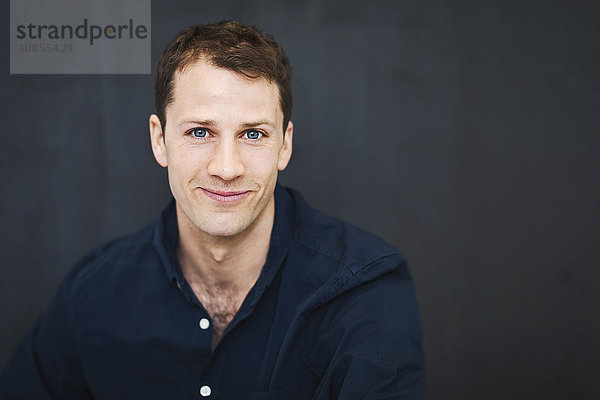 Portrait of happy mid adult businessman against wall in office