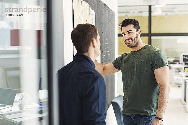 Happy young businessman with male colleague in office