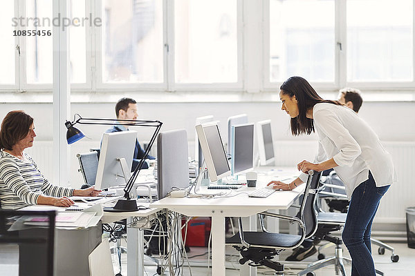 Business people using computers at desk in office