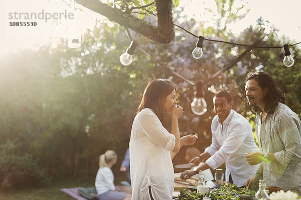 Friends preparing food together in backyard during summer party