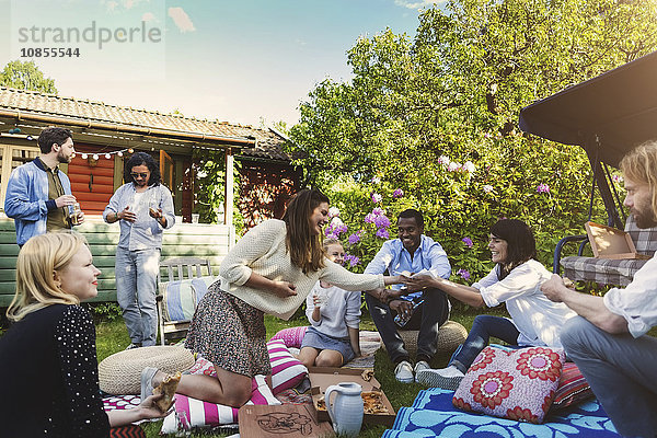 Happy woman serving food to friends in backyard during summer party