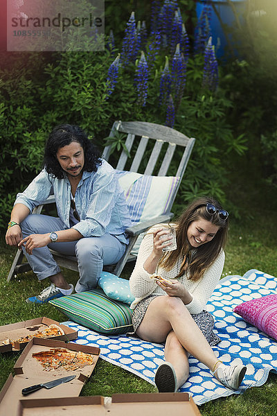 Happy man and woman enjoying while having pizza at summer party