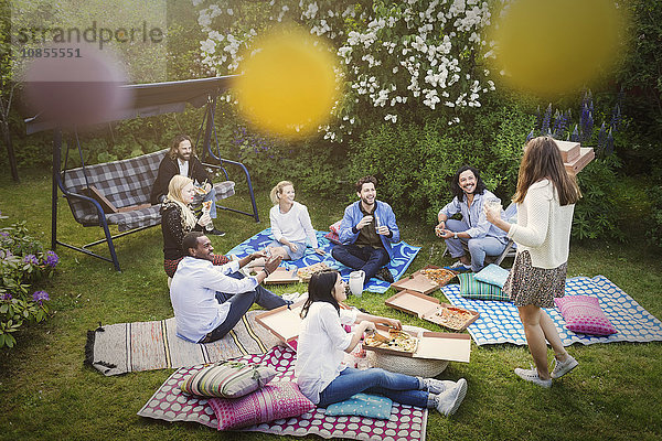 High angle view of friends having snacks during summer party at yard