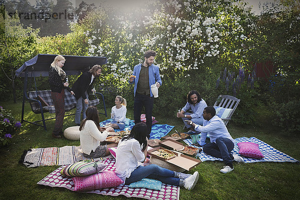 Multi-ethnic friends having snacks during summer party at yard