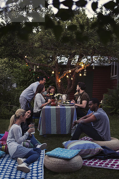 Friends relaxing at yard during dinner party