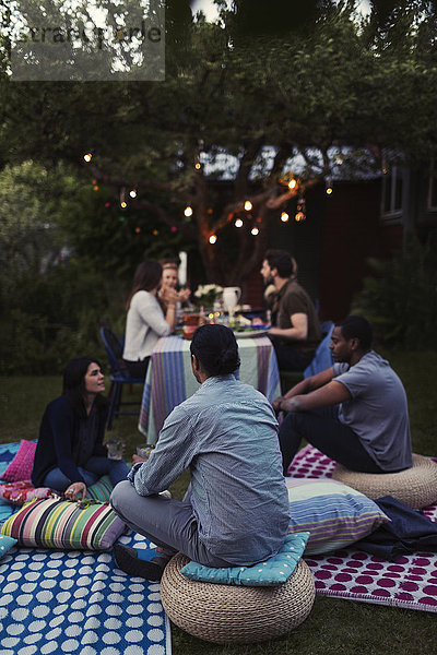 Friends relaxing by dining table during party in yard