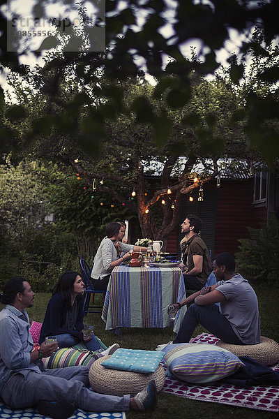 Friends communicating at dining table during party in yard