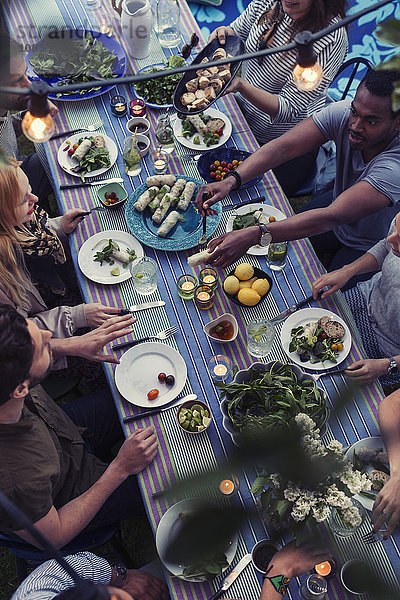 High angle view of friends having food at dining table in yard