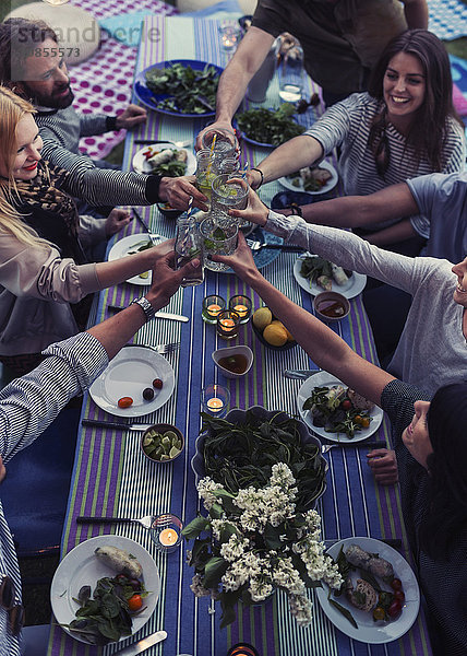 High angle view of multi-ethnic friends toasting drinks at dinner table in yard