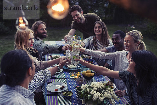 Happy multi-ethnic friends toasting drinks at dinner table in yard