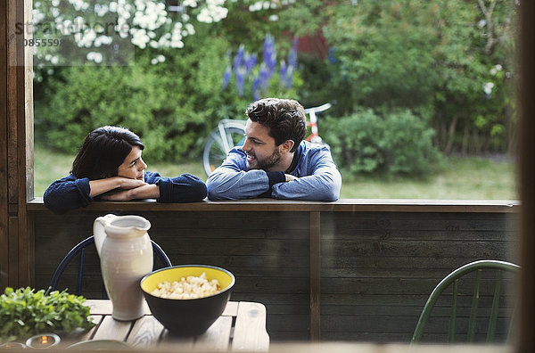 Loving couple looking at each while leaning on log cabin