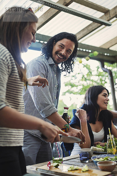 Happy friends standing at food table in log cabin