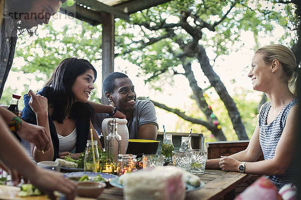 Happy multi-ethnic friends having food at porch in log cabin