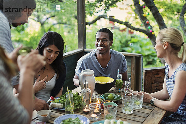 Multi-ethnic friends having food at porch in log cabin