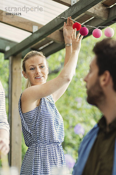 Smiling woman looking at man while decorating log cabin for summer party