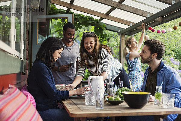 Happy friends enjoying party at porch in summer house