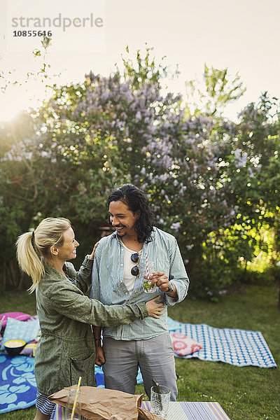 Happy woman looking at man holding drink bottle during summer party