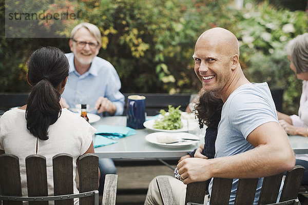 Side view portrait of happy man enjoying meal with family at outdoor table