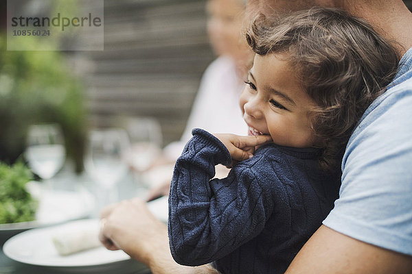 Happy girl sitting with father having food at outdoor table