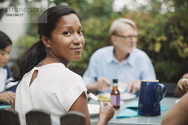 Rear view portrait of woman having food with family at outdoor table