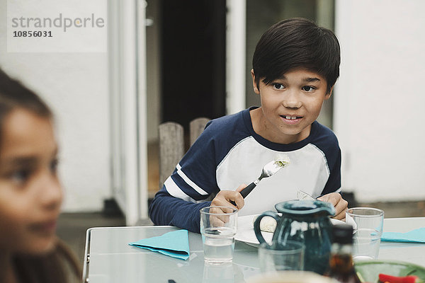 Boy looking away while having food at outdoor dining table