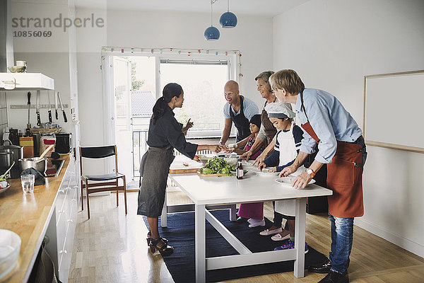 Woman assisting family in preparing Asian food at kitchen