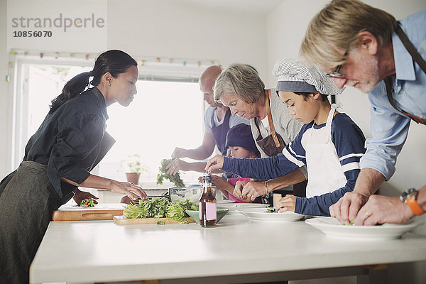 Woman guiding family in preparing Asian food at kitchen