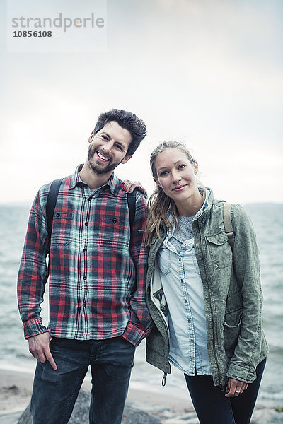 Portrait of happy wonderlust couple standing on beach