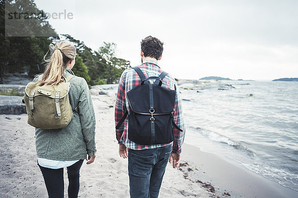 Rear view of wonderlust couple walking together on beach