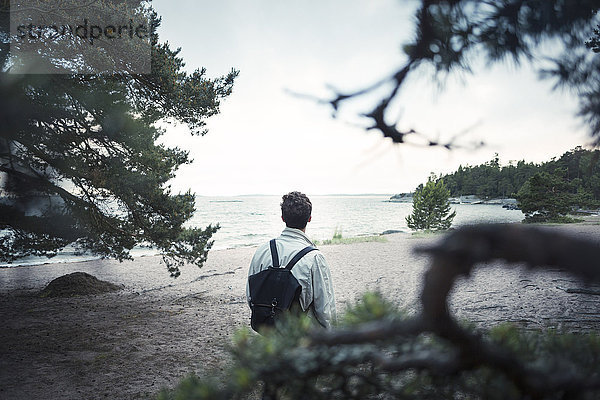 Rear view of man standing at lakeshore