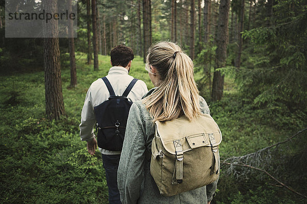 Rear view of wonderlust couple walking through forest