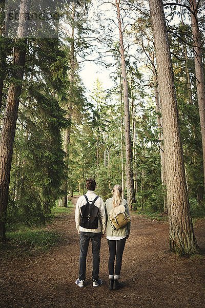 Rear view of wonderlust couple standing together in forest