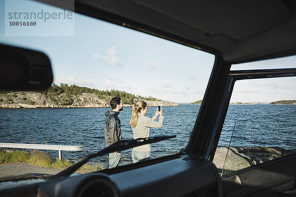 Couple seen through car windshield at lakeshore