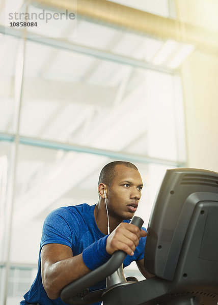 Entschlossener Mann auf Ellipsentrainer im Fitnessstudio