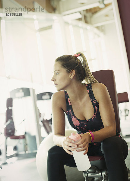 Frau mit Wasserflasche im Fitnessstudio