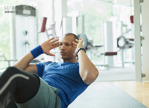 Fokussierter Mann  der im Fitnessstudio sitzt.