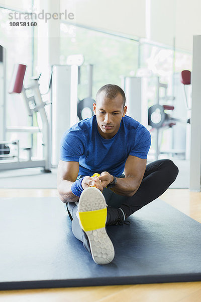 Mann mit Widerstandsband zum Strecken des Beines im Fitnessstudio