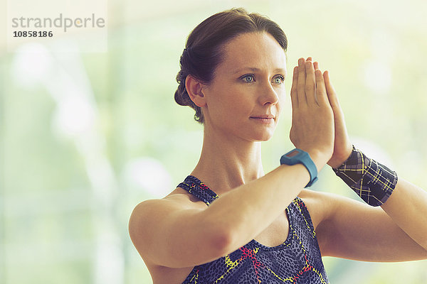 Ruhige Frau mit Händen in Gebetsposition im Yogakurs