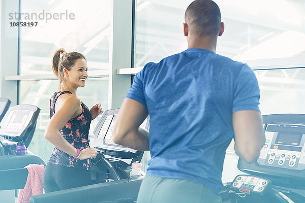 Mann und Frau joggen auf Laufbändern im Fitnessstudio