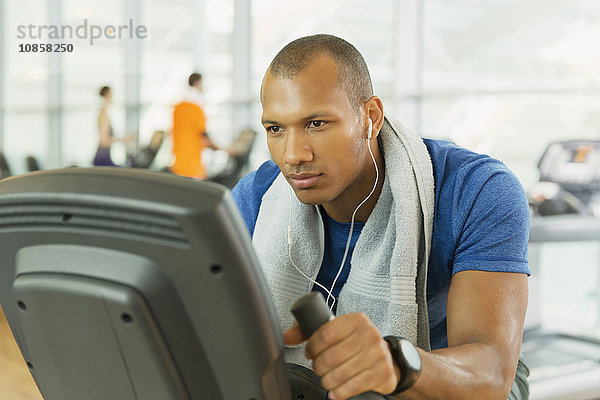 Fokussierter Mann auf dem Heimtrainer im Fitnessstudio