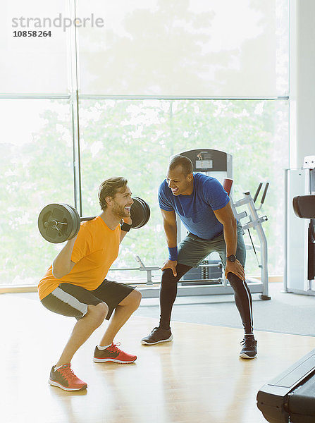 Persönlicher Trainer  der Mann führt  der Barbellhocken an der Gymnastik tut