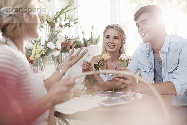 Florist bespricht Rosen mit Paar im Blumenladen