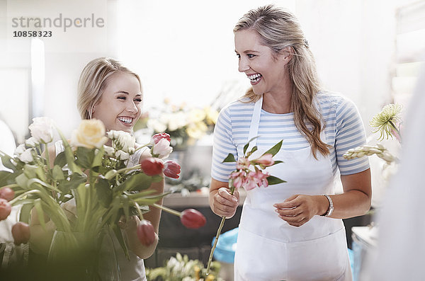 Lachende Floristen arrangieren Blumenstrauß im Blumenladen