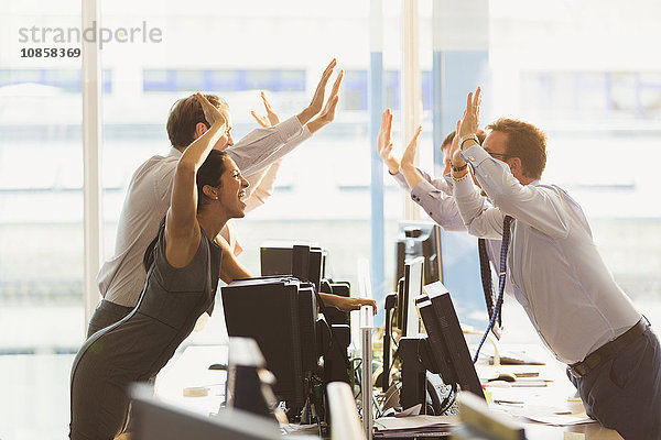 Überschwängliche Geschäftsleute  die sich über Computer im Büro freuen.