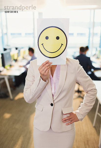 Porträt einer Geschäftsfrau mit Smiley-Gesichtsausdruck über dem Gesicht im Büro