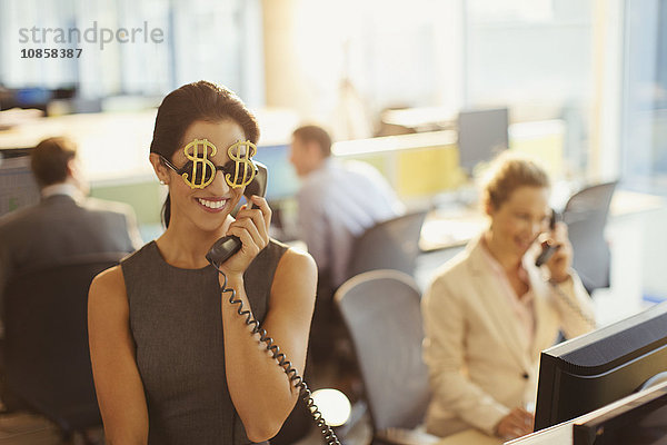 Porträt einer lächelnden Geschäftsfrau mit Dollarzeichen-Sonnenbrille am Telefon im Büro